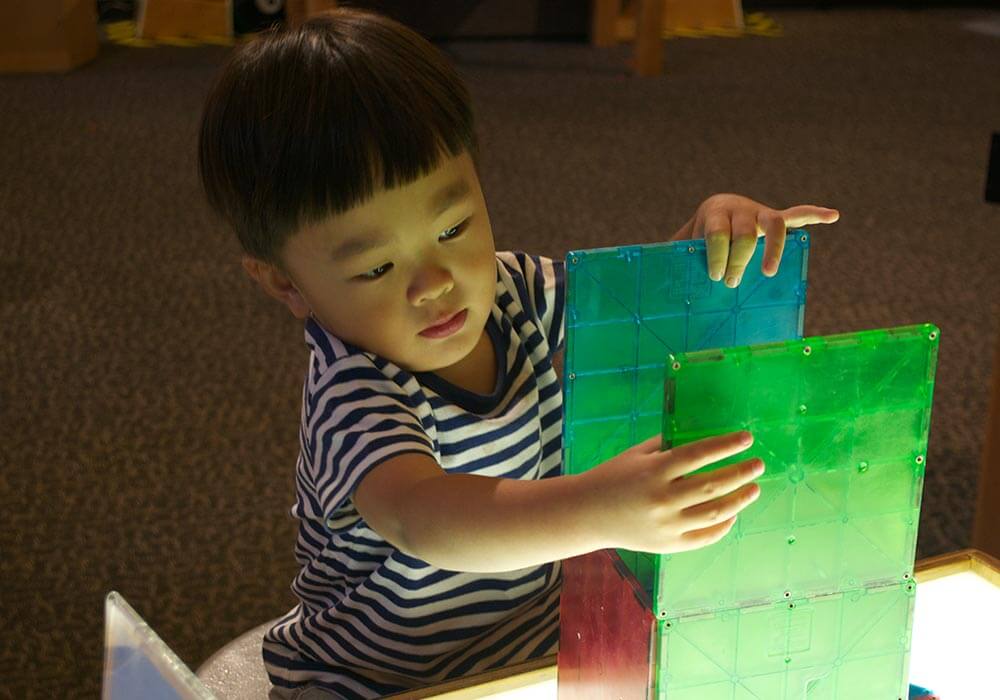 Small child plays with magnetic tiles at Wonderlab Science Museum