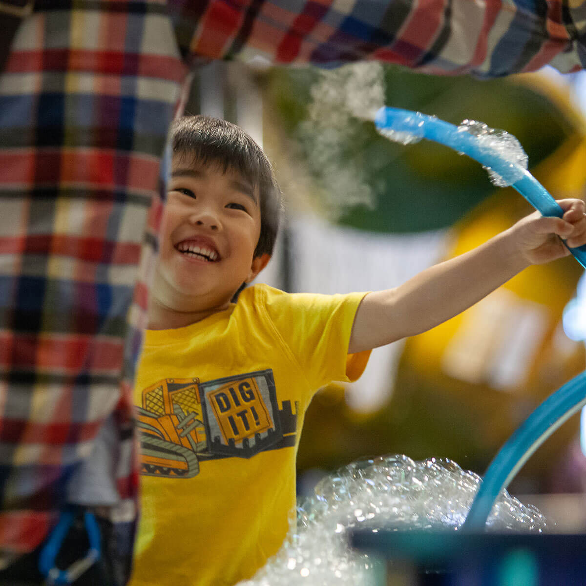 A child smiles at an adult as he plays in the bubble exhibit