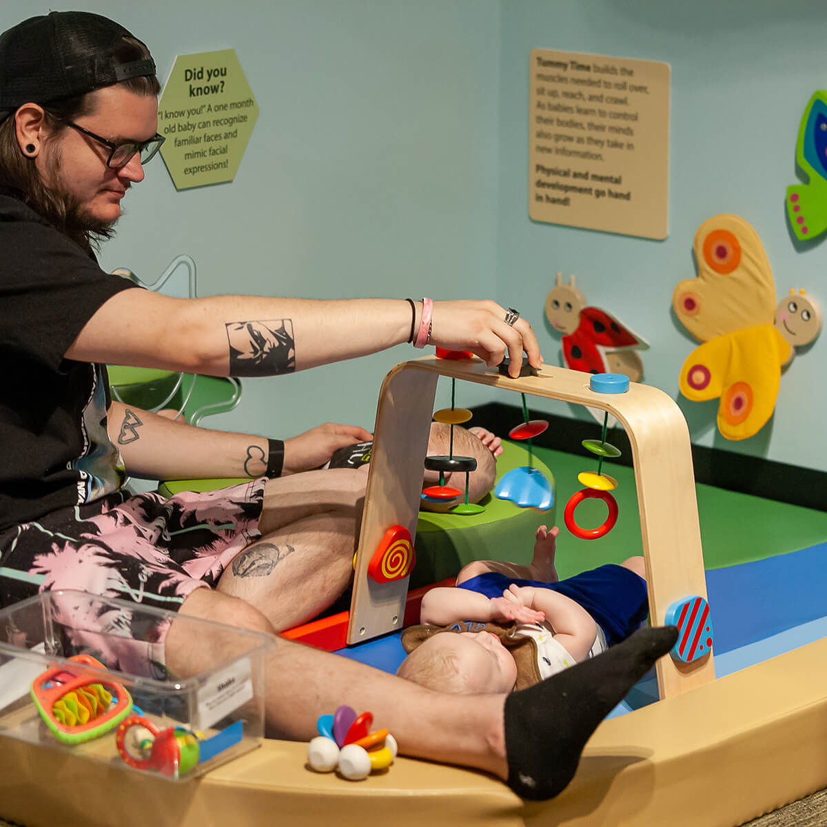 A baby plays in the Science Sprouts area of Wonderlab with their caregiver