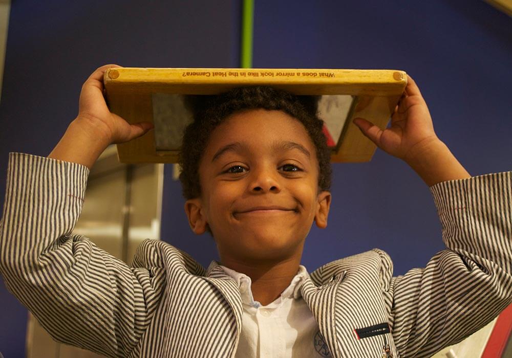 Smiling child balances a book on his at Wonderlab Museum in Bloomington, IN