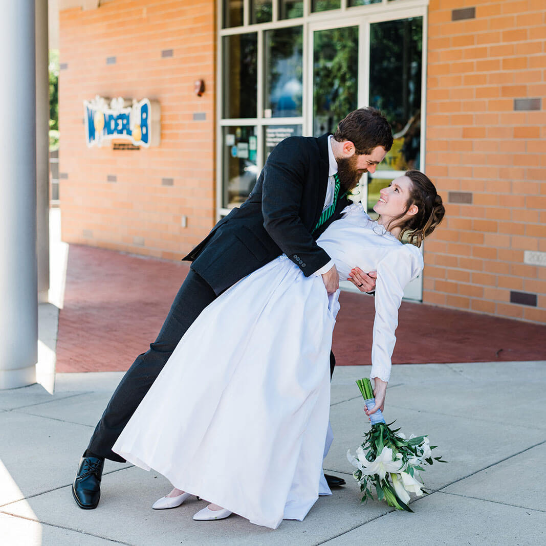 Groom holds bride in his arms outside Wonderlab wedding venue in Bloomington IN