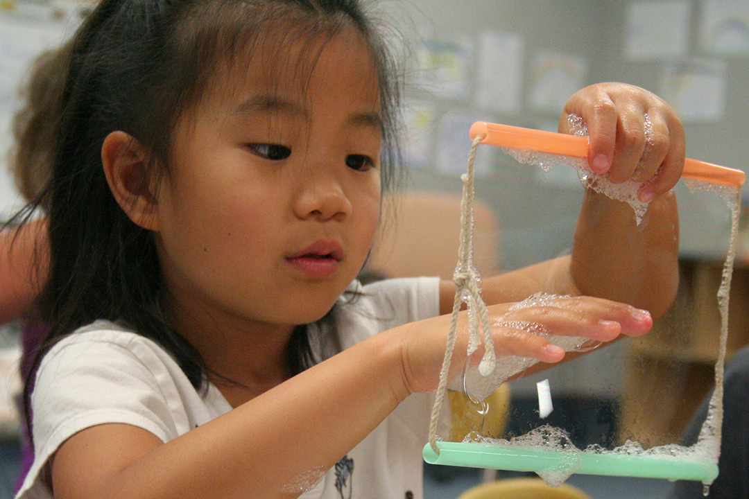 Child is examining a bubble during Wonderlab STEAM camp
