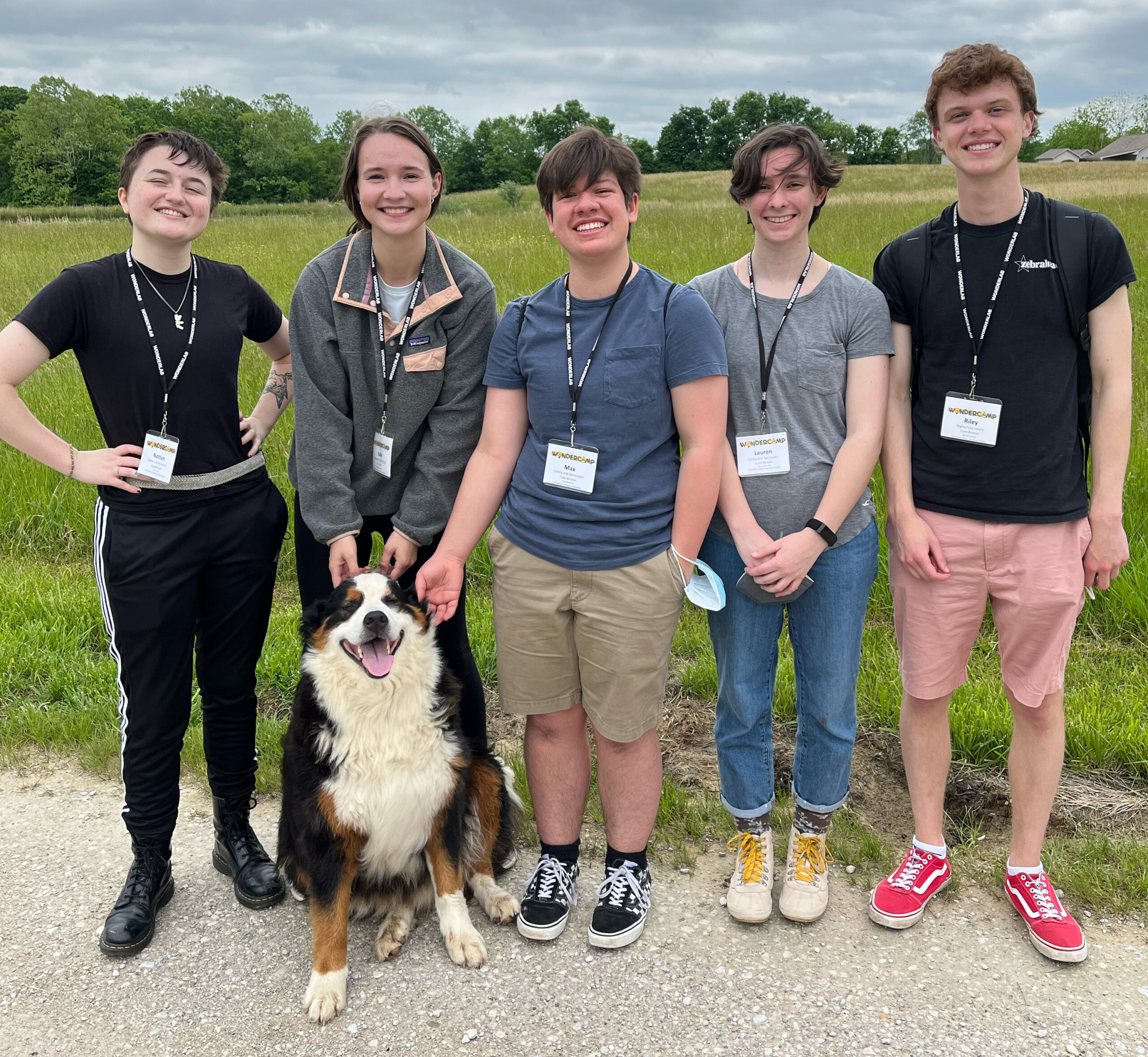 5 smiling Wonderlab interns stand with a dog outdoors