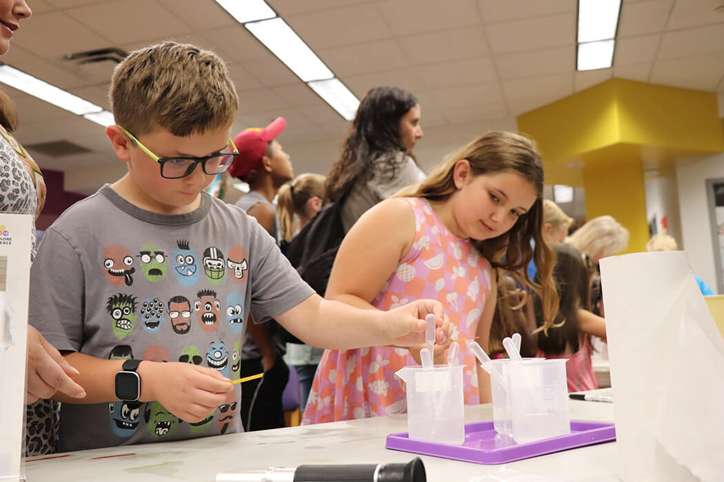 Two elementary-aged kids are focused on a science experiment at a WonderLab Wonderfest event