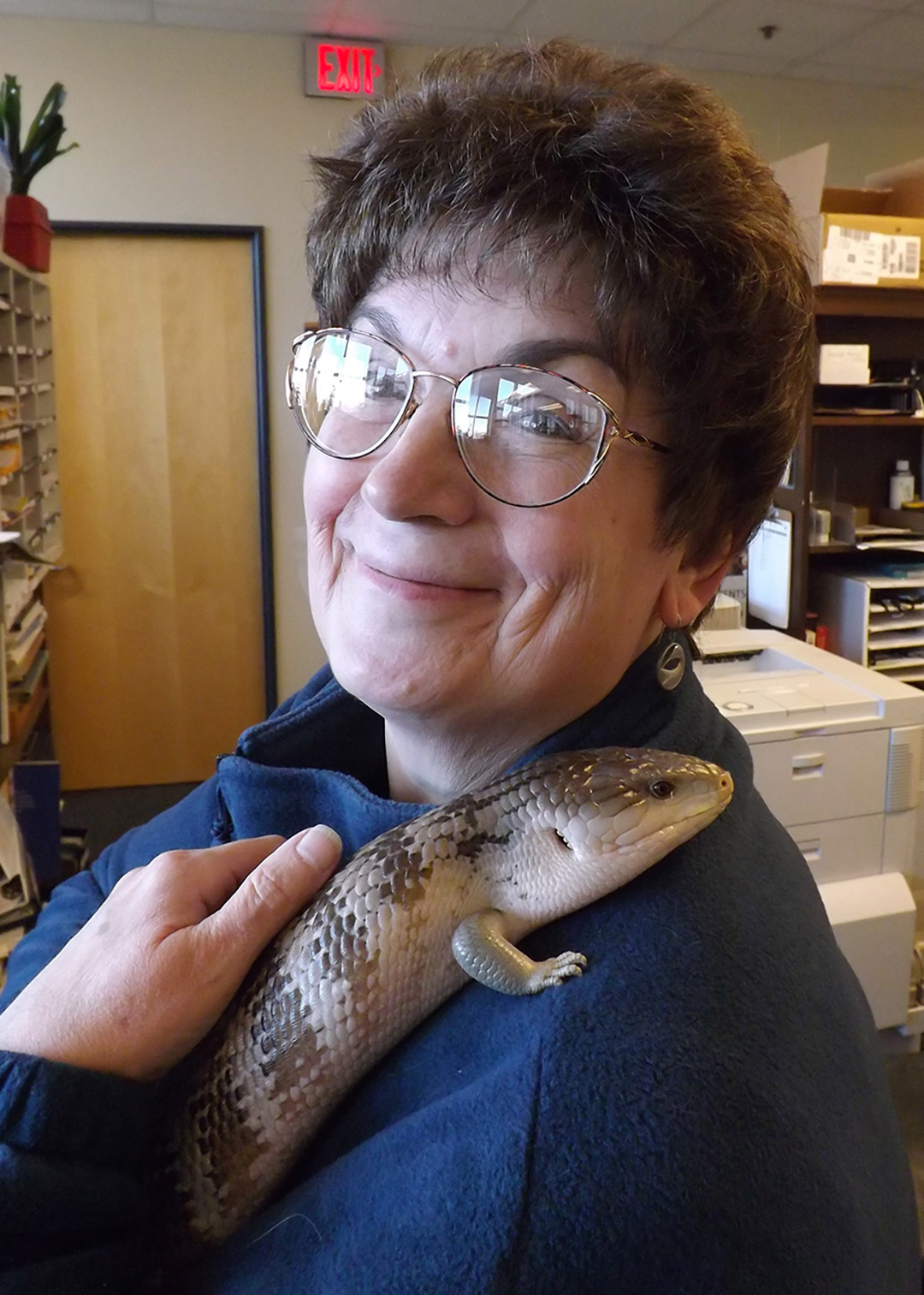 WonderLab Founding Executive Director, holding Mooch, the blue-tongued skink, smiles for the camera.